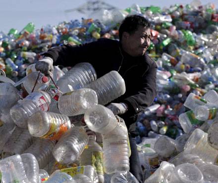 A person diligently sorts through a large pile of recycling plastics at the site.