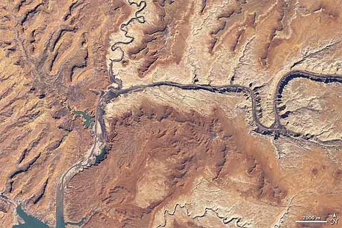 Aerial view of a desert landscape with the Colorado River winding through rugged, brown terrain.